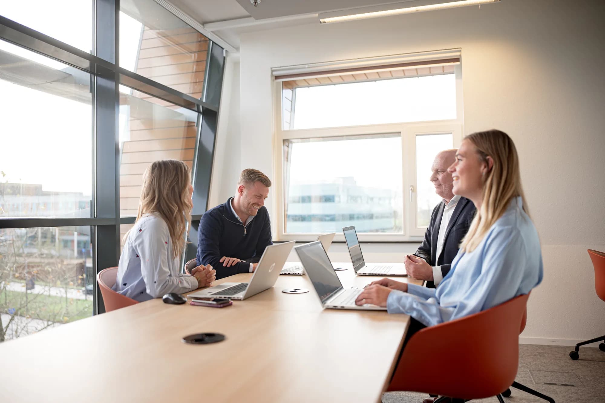 Vier collega’s bespreken projectresultaten tijdens een overleg in een moderne kantooromgeving.
